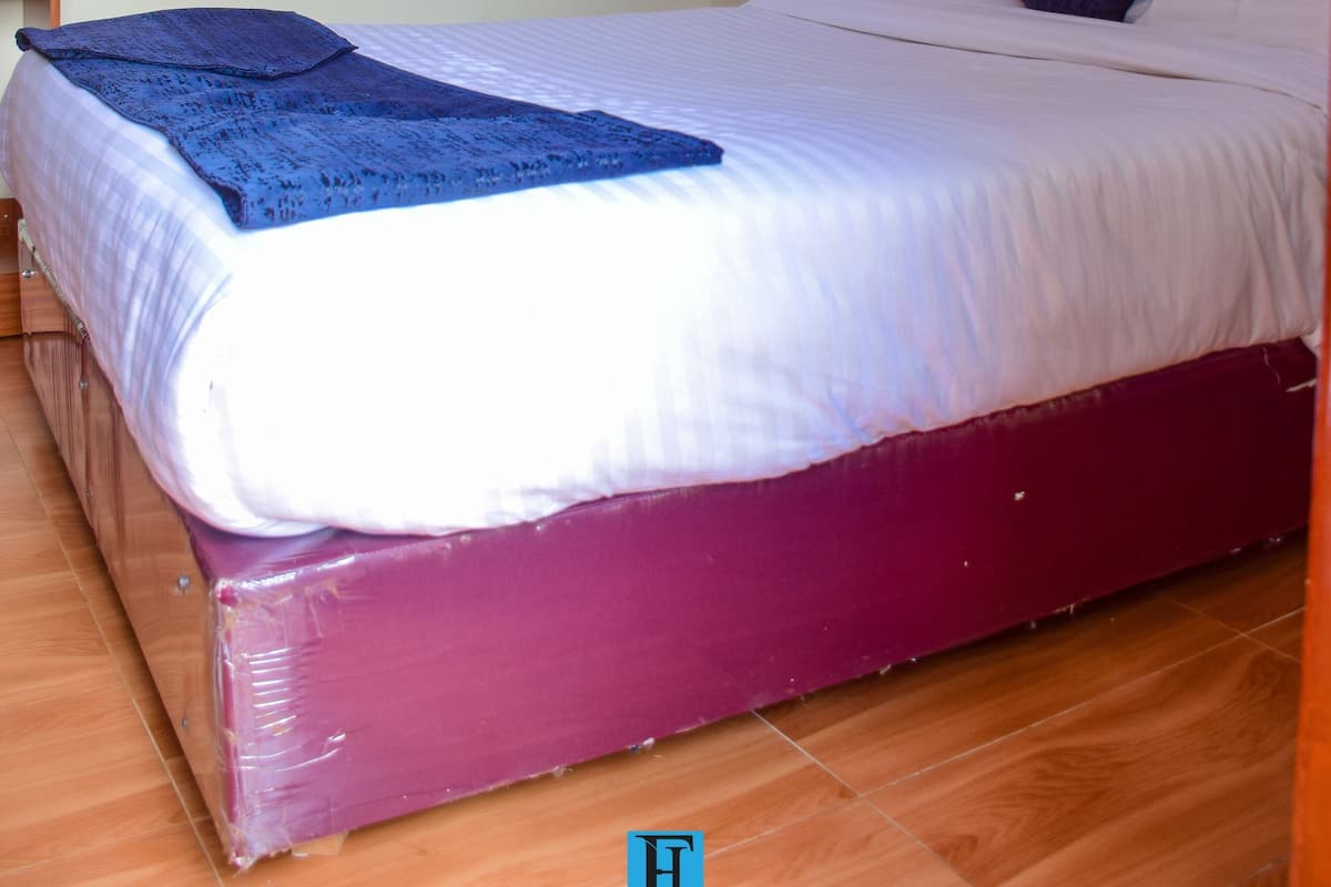 A single bed with a white canopy, a purple mattress, and a blue blanket.
