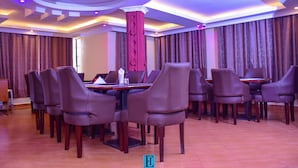 A conference room with a round table, multiple chairs, and a decorative pillar.