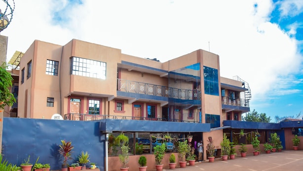 A multi-story building with a flat roof, a balcony on the second floor, and a blue awning over the entrance.