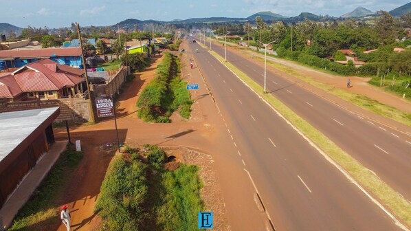 A road with a sign for EBISA HOTEL, a paved road, and a dirt path. - EBISA HOTEL MARSABIT (Marsabit)