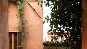 A narrow alleyway with a building on one side and a tree on the other. - Relais del Portico (Rome)