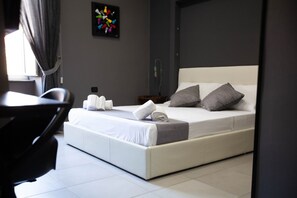 A modern hotel room with a neatly made bed, a chair, and a small table. - TRACK 60 - PRIVATE ROOMS GARIBALDI (Naples)