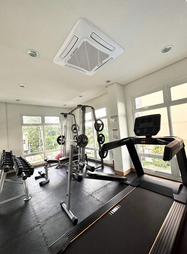 A gym with a treadmill, weight bench, and various exercise equipment.
