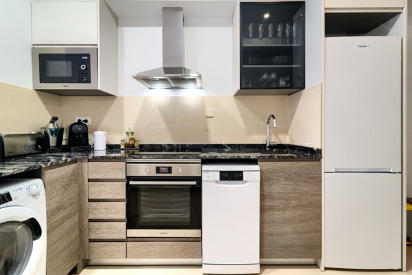 Eine moderne Küche mit integrierten Geräten, darunter Mikrowelle, Backofen, Geschirrspüler und Kühlschrank.