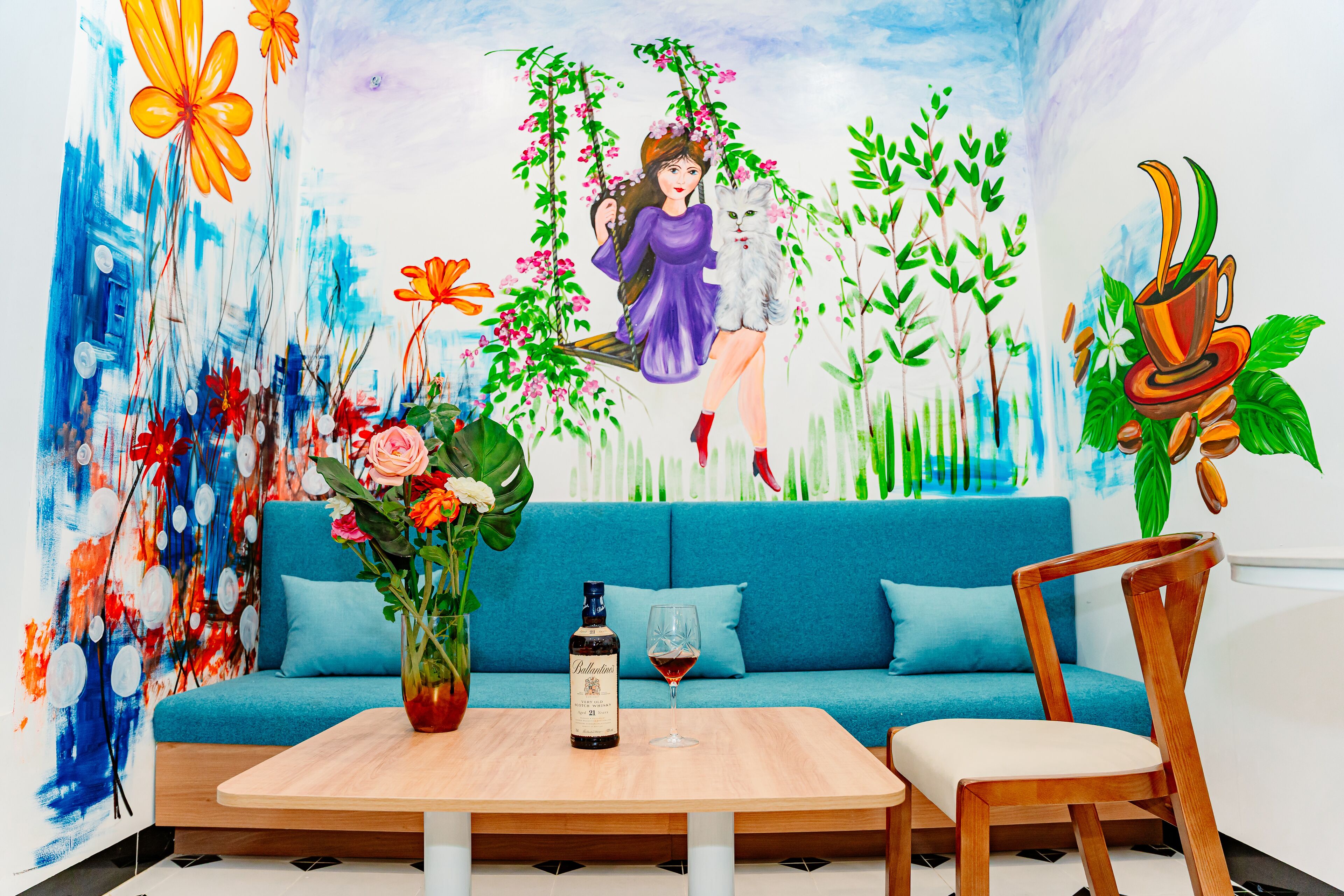 Ein Zimmer mit einem blauen Sofa, einem Holztisch mit Flasche und Glas sowie einem Stuhl.