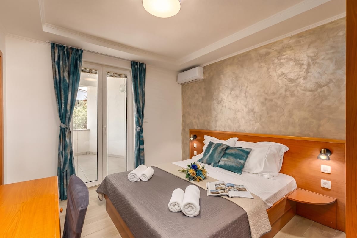 Une chambre d’hôtel avec un lit, une petite table, une chaise, une table de chevet, une lampe et une vue sur l’extérieur.