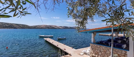 A waterfront property with a dock, lounge chairs, and a covered seating area.
