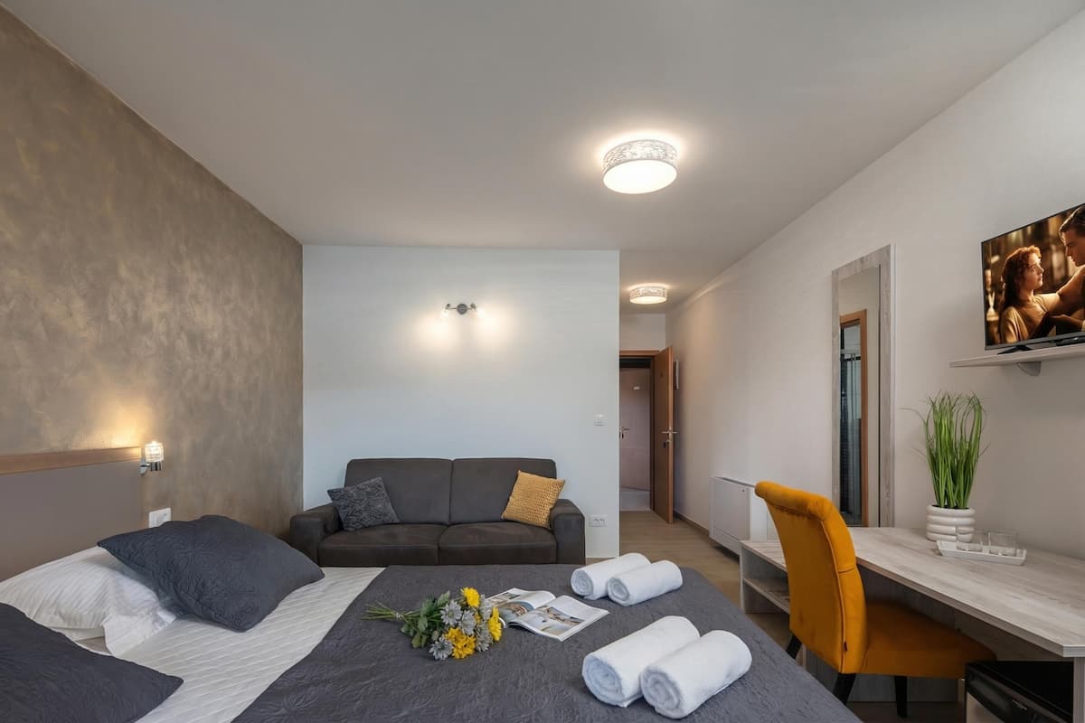 Une chambre d’hôtel avec un lit, un canapé, un bureau et un miroir.