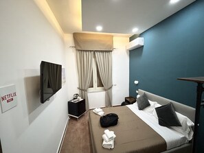 A hotel room with a bed, a TV, a desk, a chair, a window with curtains, and a sign for free Netflix. - QUEEN 20 - PRIVATE ROOMS DUOMO (Naples)