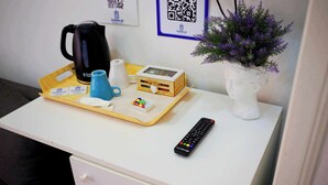 A hotel room desk with a tray containing a black coffee maker, a white mug, a blue cup, a small wooden box, a remote control, and a potted plant. - QUEEN 20 - PRIVATE ROOMS DUOMO (Naples)