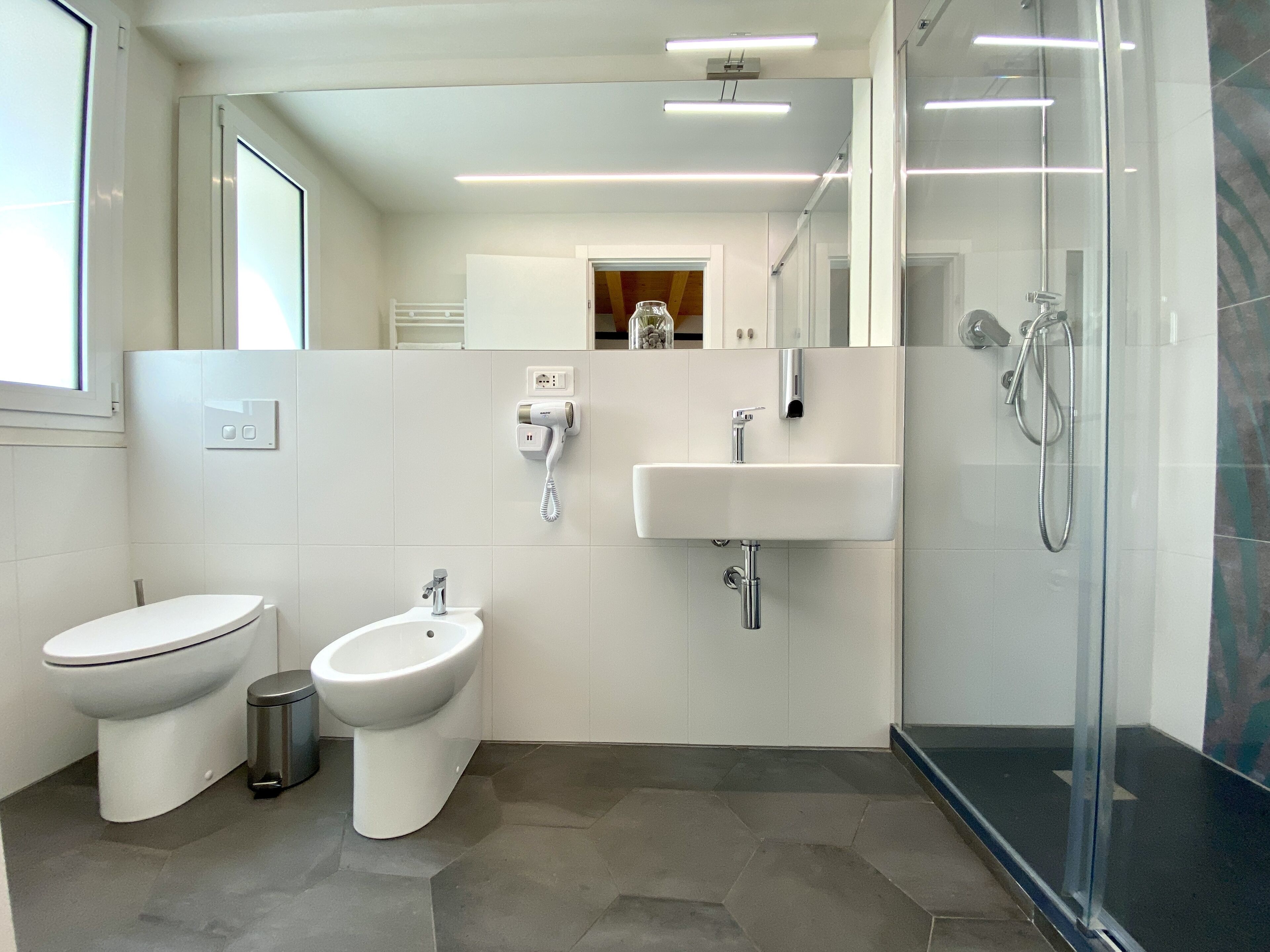 A modern bathroom with a toilet, bidet, sink, and shower.