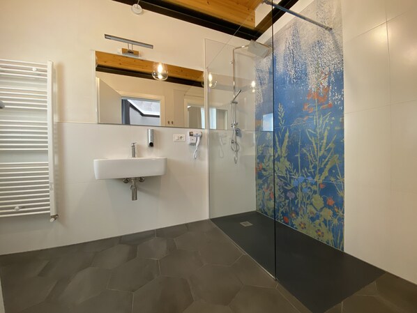 Un baño moderno con cabina de ducha de vidrio, un lavabo blanco y un espejo sobre él.