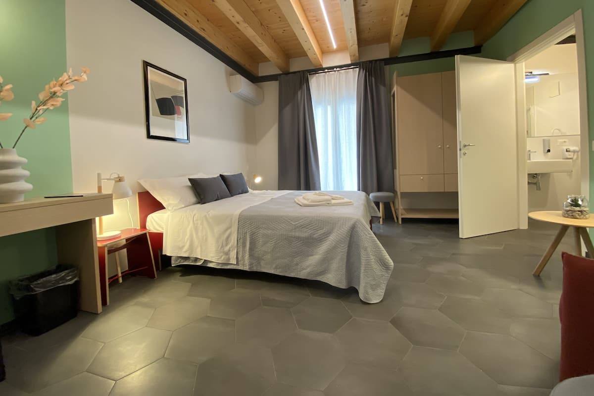 Une chambre à coucher avec un lit, une table de chevet, une lampe et une vue sur la salle de bain.