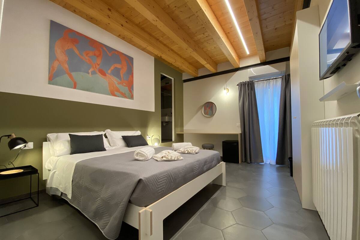 Une chambre à coucher moderne avec un lit, un tableau, un téléviseur et un radiateur.