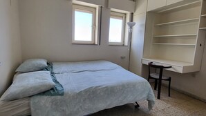 A bedroom with a bed, two windows, a ceiling fan, a desk, and a chair. - Beautiful views - walk to restaurants, theaters, First Station, & Old City (Jerusalem)