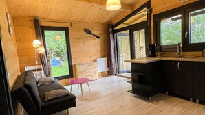 A cozy wooden interior with a sofa, dining table, and kitchen area.