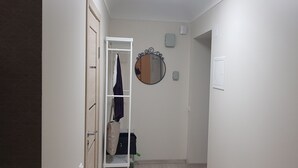 Ein Flur mit Garderobe, Spiegel und einer Tür zu einem Zimmer.