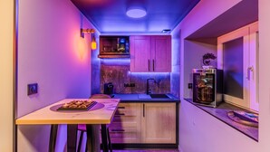 Una cocina estrecha con una mesa de comedor, armarios de madera, horno empotrado e iluminación debajo de los armarios.