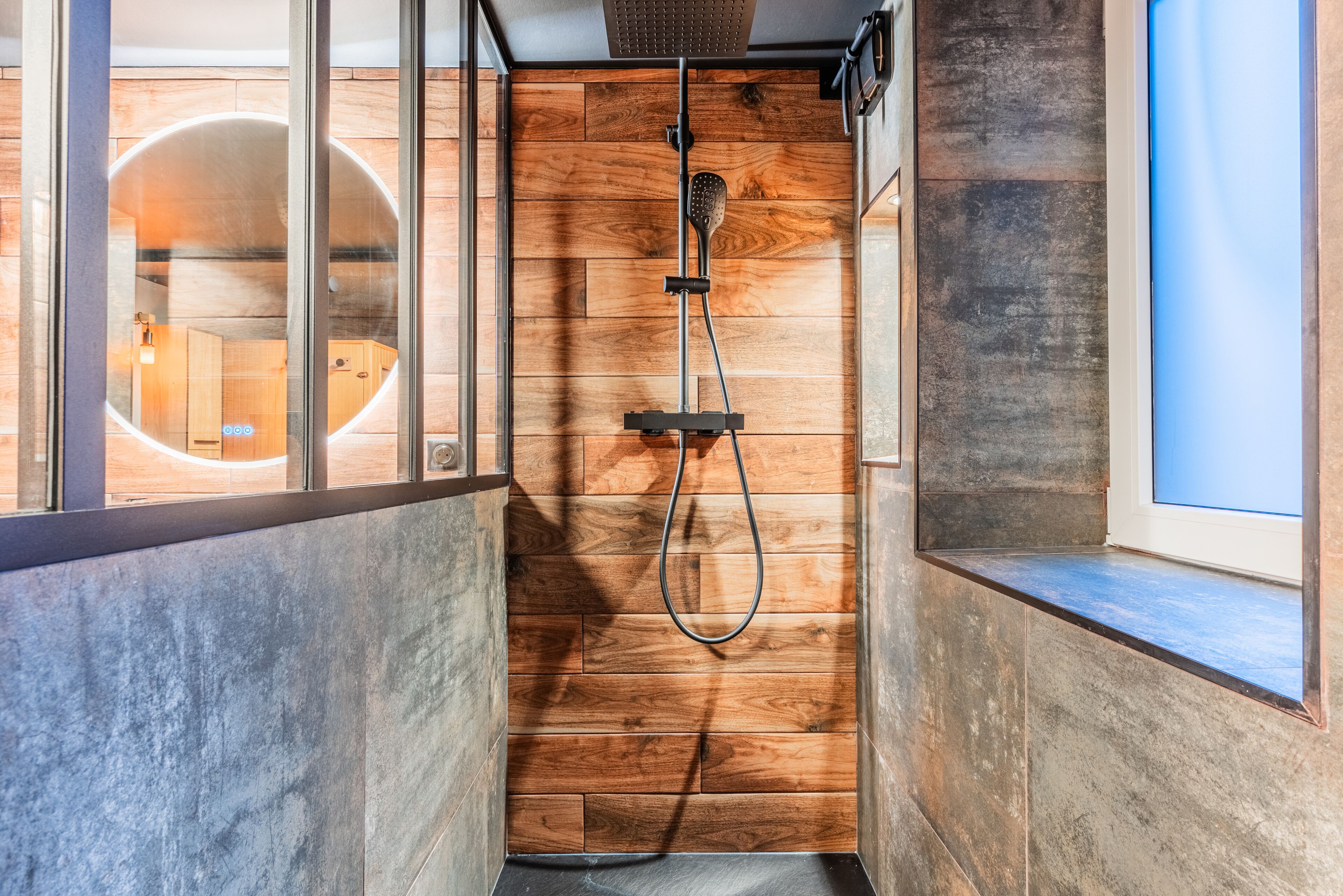 Une douche moderne avec un revêtement mural en bois et une paroi en verre.