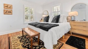 Un dormitorio con cama, mesita de noche, cómoda y un espejo grande.