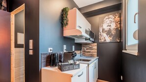 Una cocina compacta con barra de café, microondas y lavamanos.