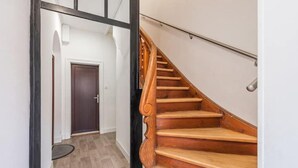 Una escalera de madera con barandilla que conduce a una puerta al final.