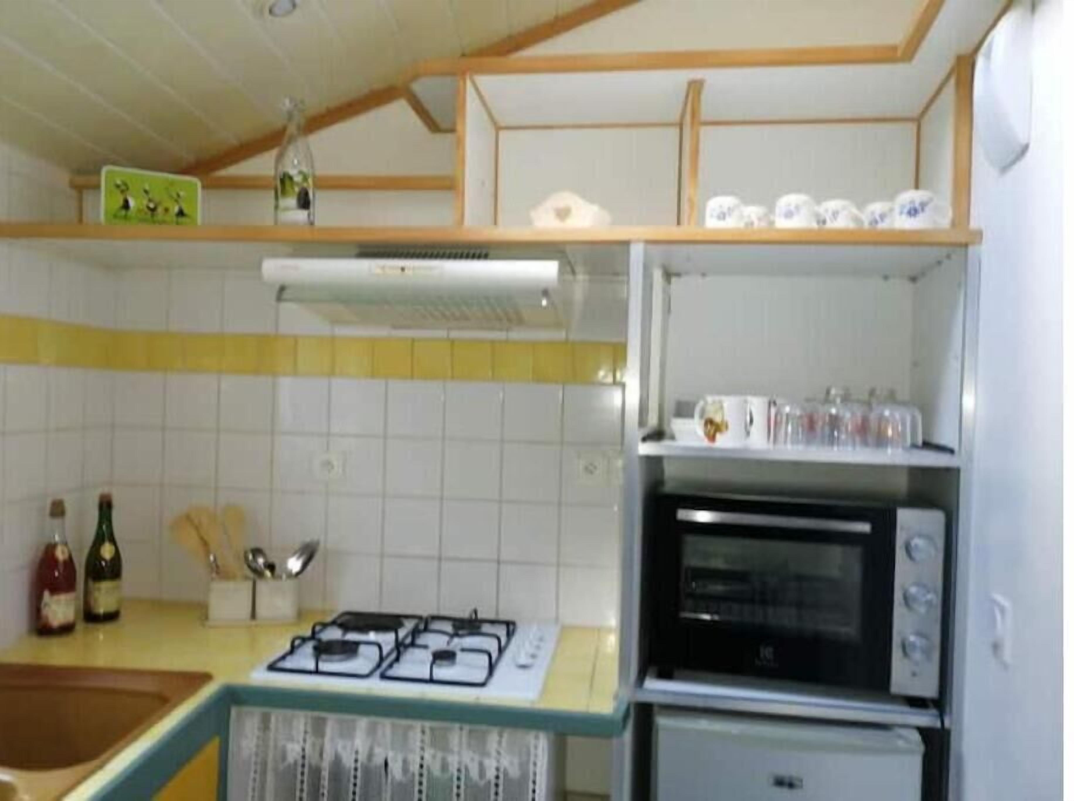 A kitchen with a gas stove, oven, and a microwave. There are bottles and utensils on the counter.