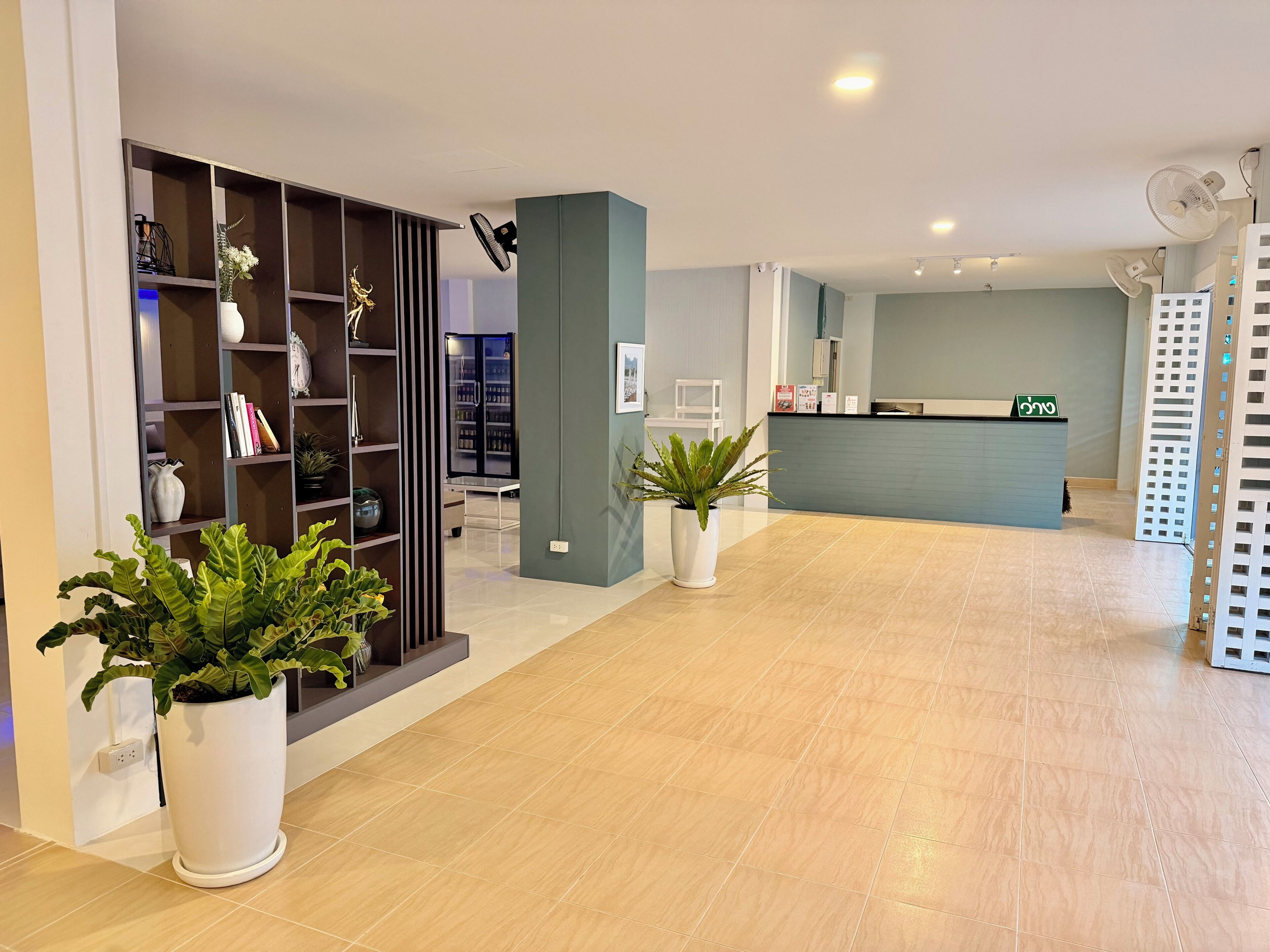 Zona de recepción con mostrador, plantas en macetas, estantería y diseño de interiores moderno.
