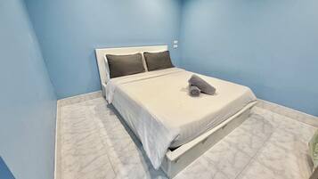 A bedroom with a bed, pillows, and a rolled towel.