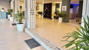 A modern hotel lobby with a reception desk, potted plants, a seating area, and a bookshelf. - The Beach INN Cha-Am (Cha-am)