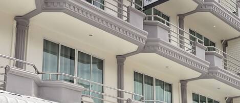 Un hotel de varios pisos con balcones, ventanas amplias y un letrero que dice 'INN THE BEACH INN CHA-AM'.