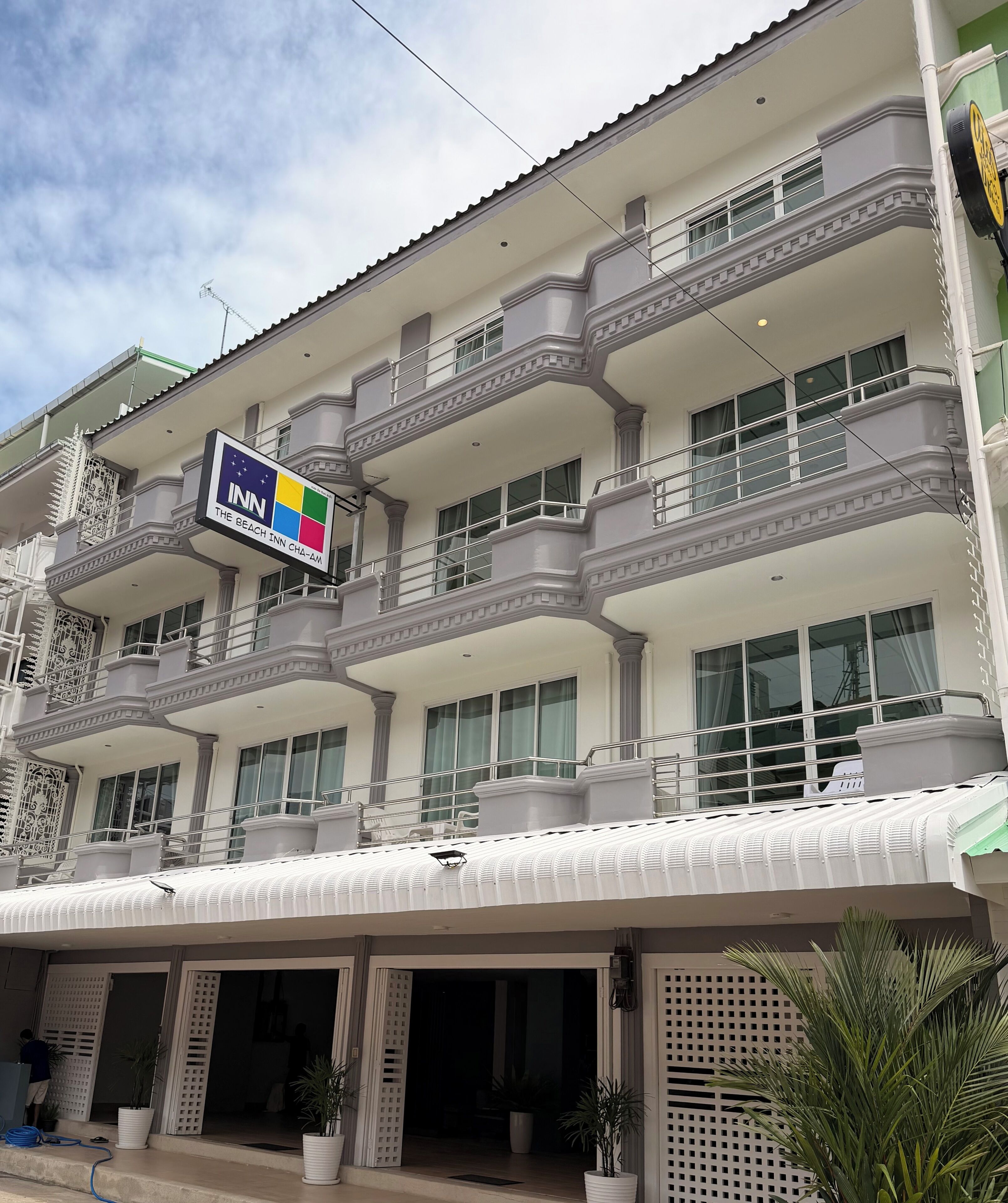 A multi-story hotel with balconies, a sign indicating it's The Beach Inn, and a gated entrance.
