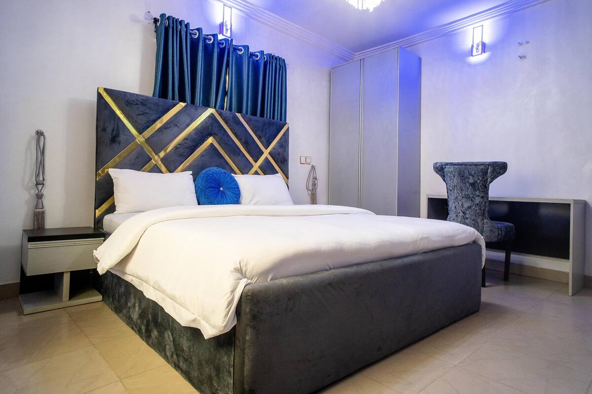 A modern bedroom with a large bed, a nightstand, a chair, and a desk.