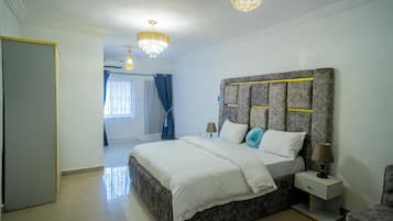 A bedroom with a large bed, a nightstand, a lamp, and a chandelier.