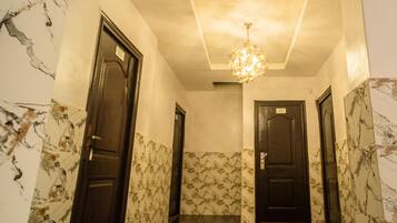 A hallway with marble walls and doors, a chandelier, and a tiled floor.
