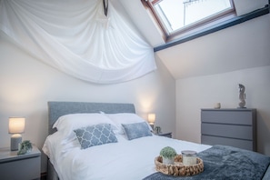 Quarto bem organizado com cama, luminárias de cabeceira, mesa de cabeceira, cômoda e janela com vista.