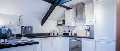 A modern kitchen with white cabinets, a black countertop, and a skylight.