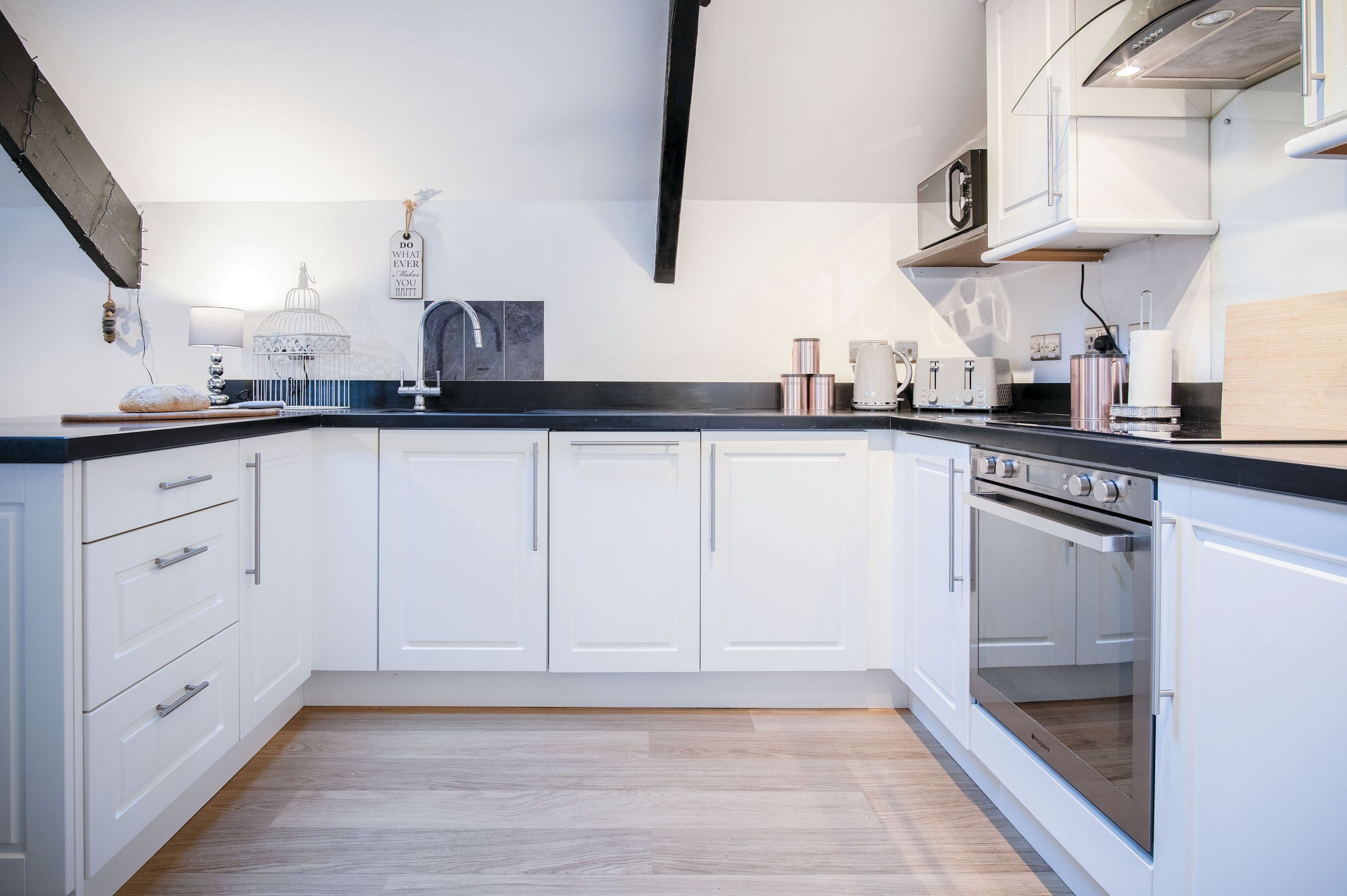 A modern kitchen with white cabinets, a black countertop, and stainless steel appliances.