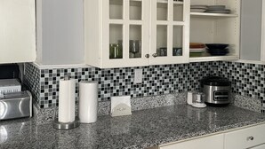A kitchen with white cabinets, a tiled backsplash, a granite countertop, and a coffee maker. - King queen, sweet cozy, and quiet old urban Neighbourhood, charming perfect stay (Birmingham)