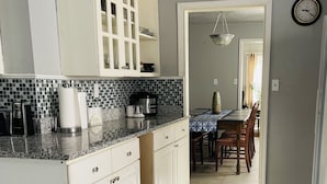 A kitchen with white cabinets, a coffee maker, and a sink. There is a dining area with a table and chairs. - King queen, sweet cozy, and quiet old urban Neighbourhood, charming perfect stay (Birmingham)