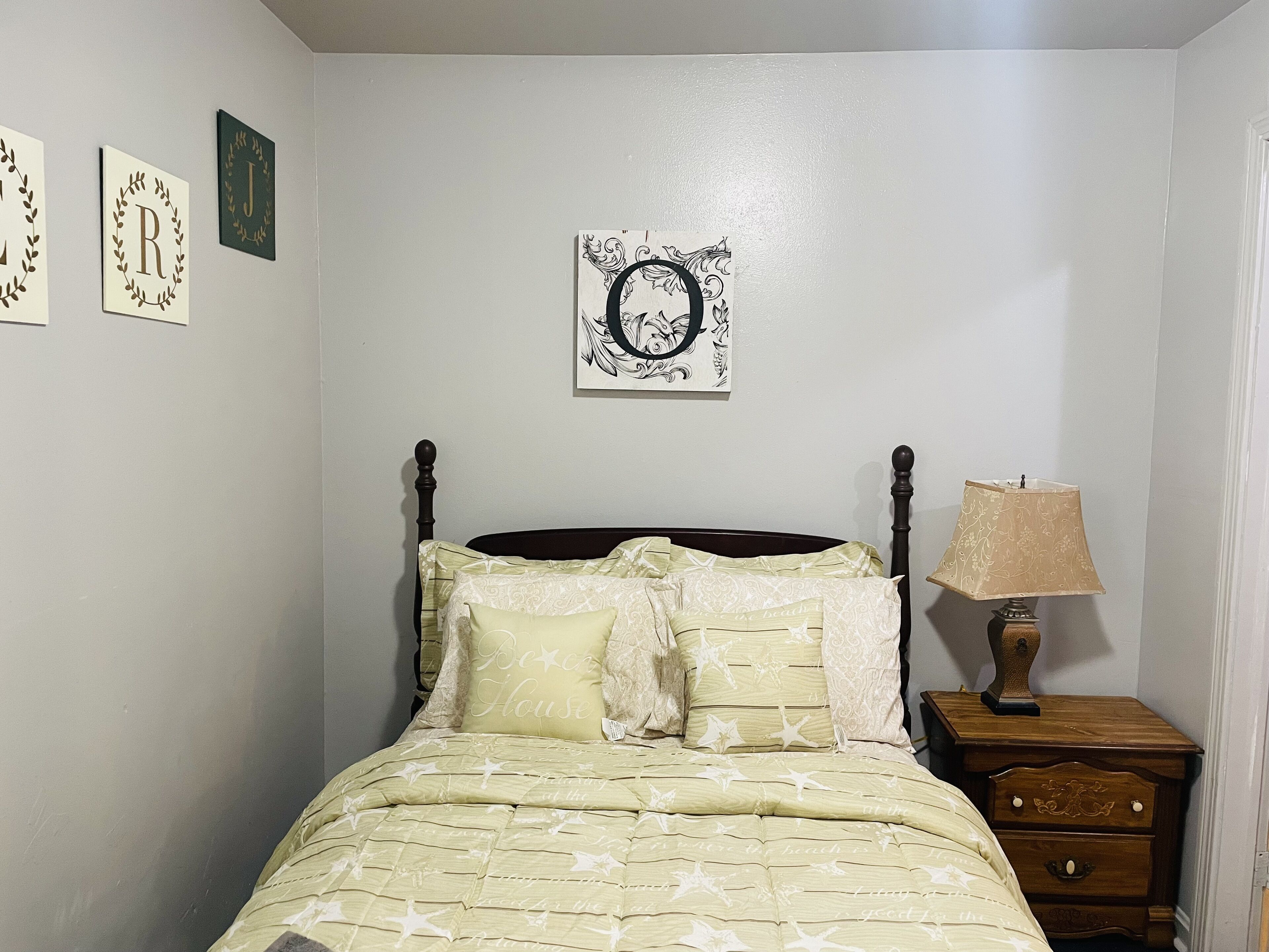 A bedroom with a bed, a nightstand, and wall decorations.