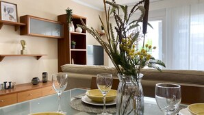 A dining table set with plates, cutlery, and wine glasses, a vase with dried plants, and a sofa in the background. - Casa cerca BCN,  ideal empresas, 15min FiraBCN, A/C (Sant Boi de Llobregat)