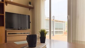 A room with a flat-screen TV mounted on the wall, a wooden table with a book and a black cup, and a potted plant. - Casa cerca BCN,  ideal empresas, 15min FiraBCN, A/C (Sant Boi de Llobregat)
