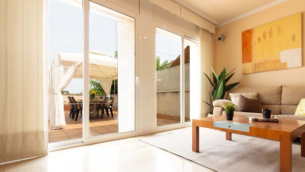 A modern living room with a sliding glass door leading to an outdoor patio, a wooden coffee table, and a beige sofa. - Casa cerca BCN,  ideal empresas, 15min FiraBCN, A/C (Sant Boi de Llobregat)