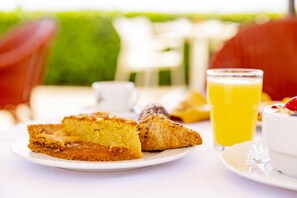A breakfast setting with a plate of pastries, a glass of orange juice, and a bowl of yogurt. - Palazzo Vittoria  (Massa Marittima)