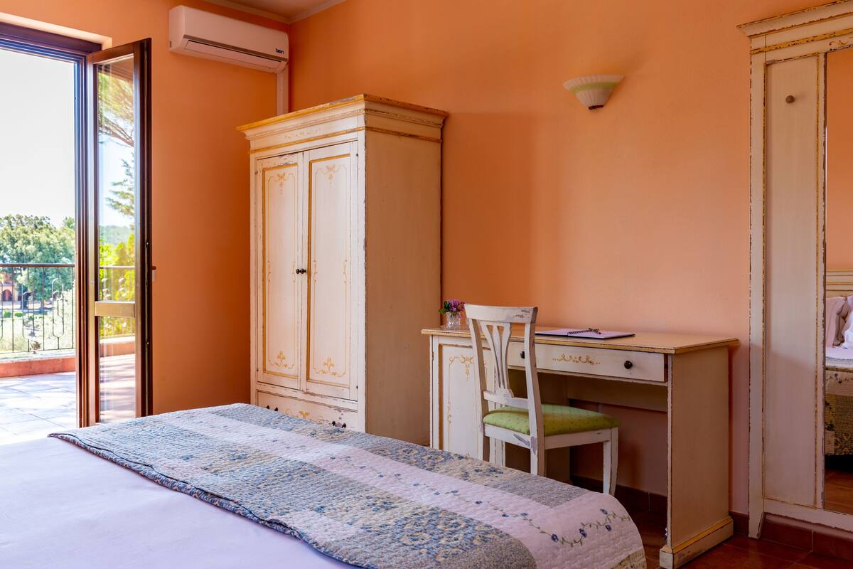 A bedroom with a bed, a desk, and a wardrobe.