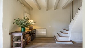 A hallway with a wooden console table, wicker baskets, a potted plant, a lamp, and a staircase. - Finca Can Romeu: Alojamiento Rural Entre Viñedos (Guardiola De Font-Rubi)