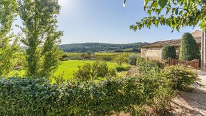A rural landscape with a vineyard, a stone building, and a clear sky. - Finca Can Romeu: Alojamiento Rural Entre Viñedos (Guardiola De Font-Rubi)