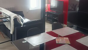 A modern living room with a dining area, a TV, and a window. - F1 Duplex Entièrement Rénové (Lamalou-les-Bains)
