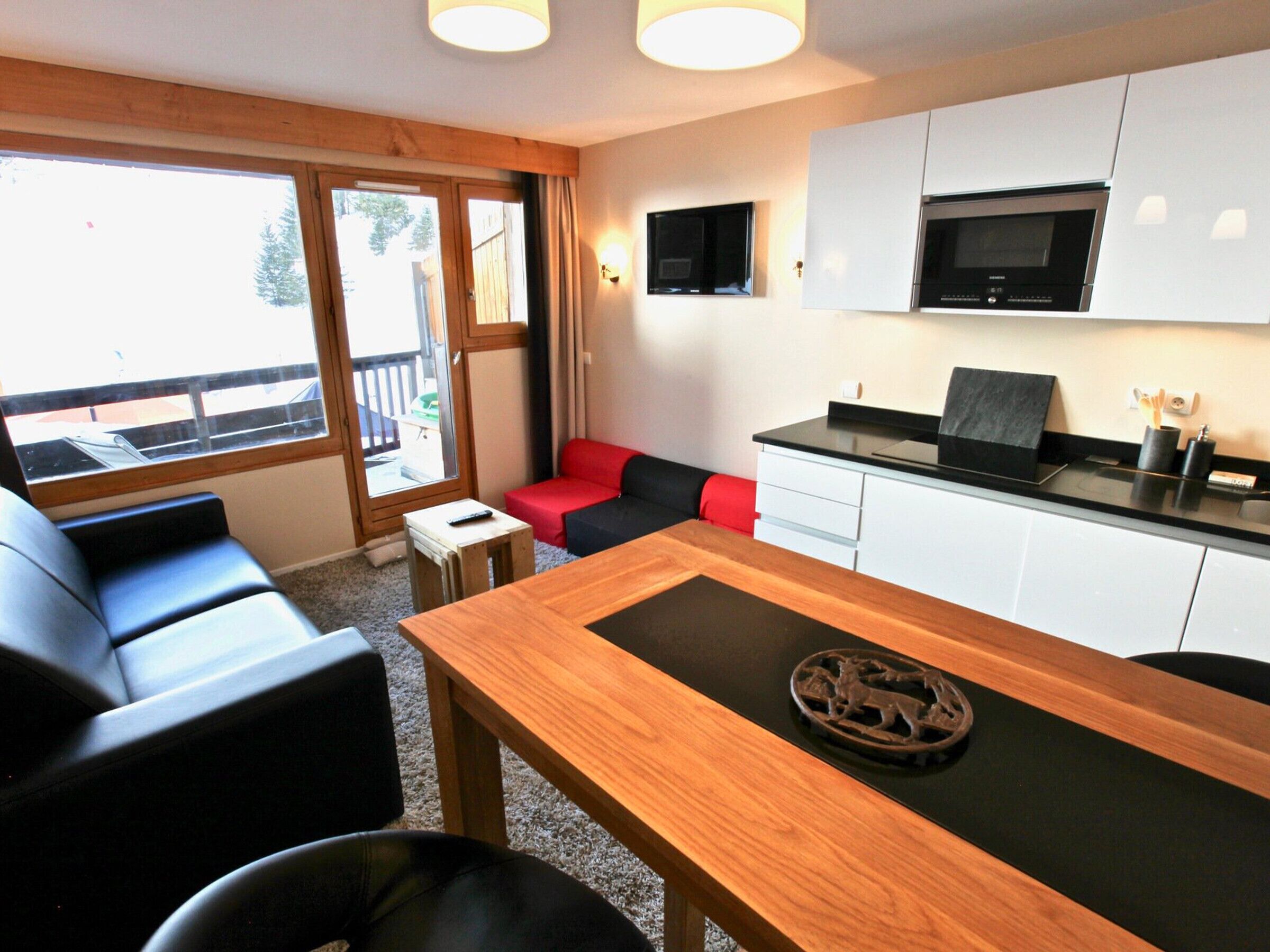 A compact living space with a dining table, a sofa, a small coffee table, and a kitchen area with a microwave and a TV.